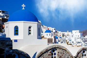 Oia town on Santorini island, Greece. Traditional houses and churches with blue domes on a blue sky.