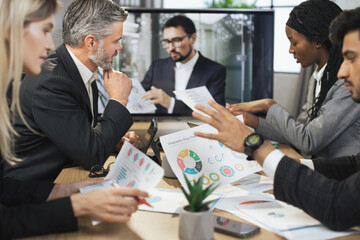 Electronic meeting concept. Diverse group of multiracial business people in the conference room with big TV screen listen to the instructions of their business colleagues during a video conference.