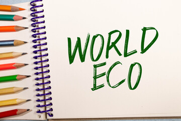 Ecological concept. On a white-green background lies a pen and a notepad with the inscription - WORLD ECO.