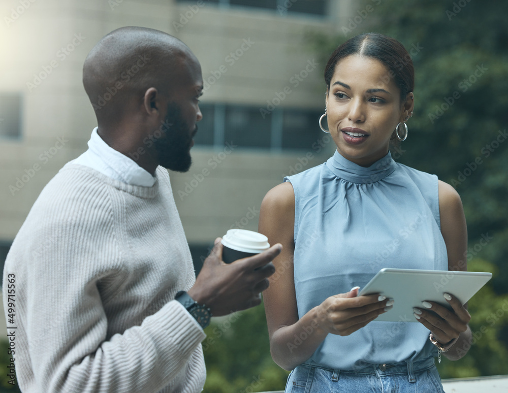 Poster keeping their eye on business at every moment. shot of two businesspeople using a digital tablet tog
