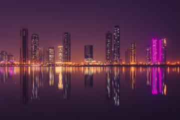 City skyline at night, tallest towers in the Emirates and its reflection on lakes at night, Dubai, Sharjah