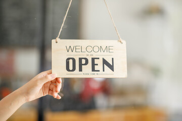 Welcome. Open. barista, waitress woman turning open sign board on glass door in modern cafe coffee shop ready to service, cafe restaurant, retail store, small business owner, food and drink concept