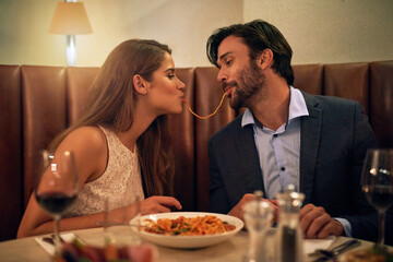 Nothing inspires romance quite like Italian food. Shot of a young couple sharing spaghetti during a...