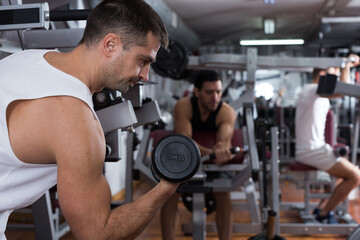 Fototapeta na wymiar Portrait of athletic man exercising with dumbbells in gym