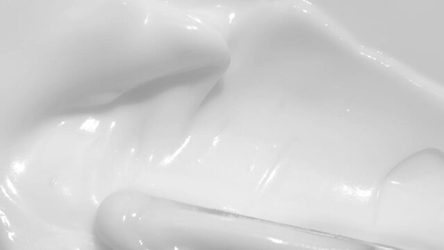 Creamy skincare lotion mousse product closeup footage. White cream, shampoo texture, sunscreen cosmetic smear background video. Moisturising beauty creme swatch motion with spatula. Macro