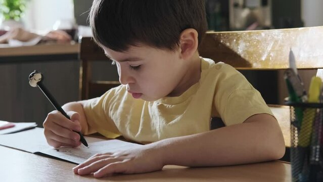 Close-up portrait of a caucasian boy, prewriting practice to prepare hands for write letters. Writing education concept. Education, learning, study.