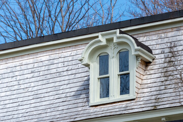 The roof of a vintage green wooden building with cream color trim, multiple double hung windows,...