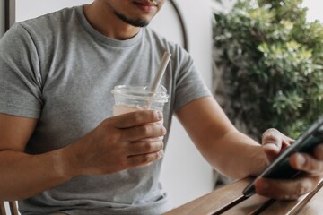 Close up of asian man use paper straw for his drink in the cafe.