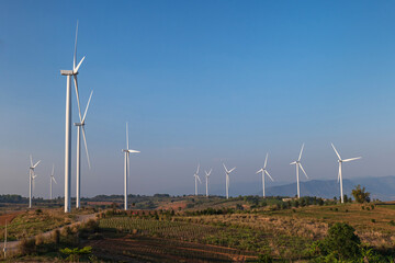 Wind turbine farm on mountain landscape with blue sky background. Wind power renewable energy concept.