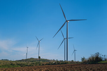 Wind turbine farm on mountain landscape with blue sky background. Wind power renewable energy concept.
