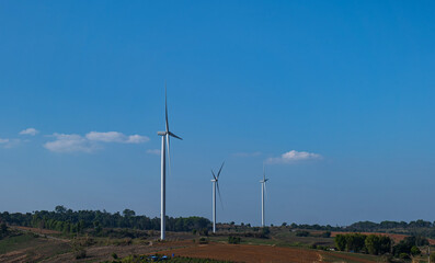 Wind turbine farm on mountain landscape with blue sky background. Wind power renewable energy concept.