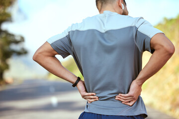 Fototapeta premium Take it one day at a time. Rearview shot of an unrecognisable man holding his lower back in pain while exercising outdoors.