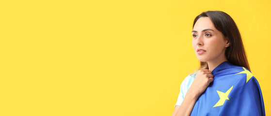 Beautiful young woman with flag of European Union on yellow background with space for text
