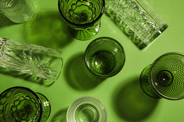 Different empty glasses on green background, top view