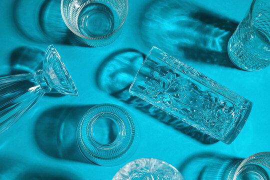Different empty glasses on blue background, top view