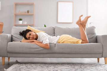 Young barefoot woman lying on sofa at home