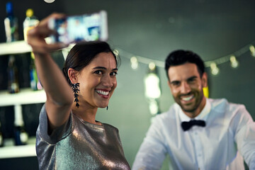 I want to remember this night. Shot of a young woman taking a selfie with the bartender in a nightclub.