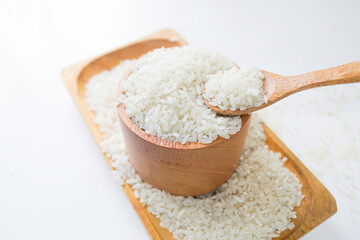 Rice on wooden spoon and wooden bowl