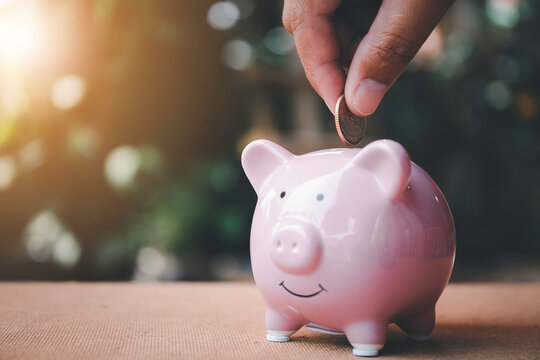 Closeup image  holding coins putting in piggy bank. concept saving money for finance accounting