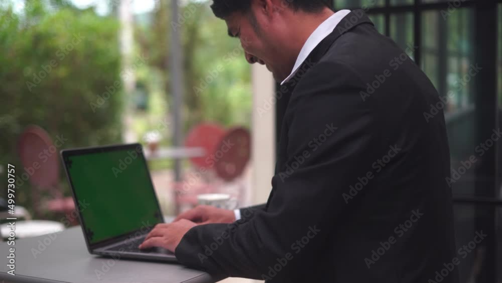 Poster Close-up of green notebook computer screen with the fingers of a man in a business suit typing on a keyboard
