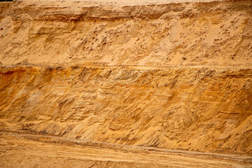 Textural sand, with  relief surface, multi-colored layers and different in size of granules, in outdoor sand career, after mining ore and sand for construction.