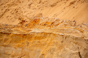 Textural sand, with  relief surface, multi-colored layers and different in size of granules, in outdoor sand career, after mining ore and sand for construction.