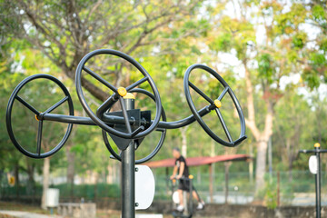 Exercise or fitness equipment, Double Stretching Wheel n the park, with out of focus man exercising in the background.