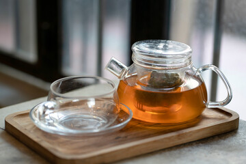 Warm tea in a teapot and cup on a wooden tray. Ready to serve.