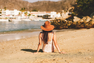 Latin woman sitting on the beach, enjoying the sunset. Woman reading book. Woman on the beach of...