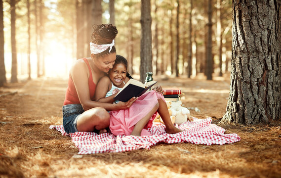 Spark your childs imagination and stimulate curiosity through reading. Shot of a mother and her little daughter reading a book together in the woods.