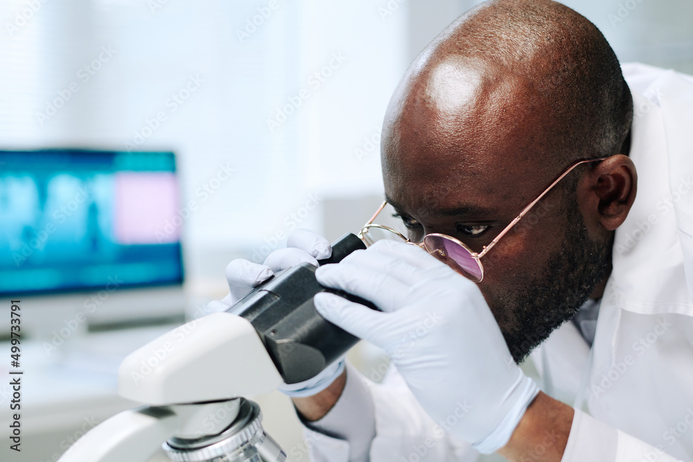 Poster bald african american scientist in gloves and eyeglasses looking at new virus or bacteria in microsc