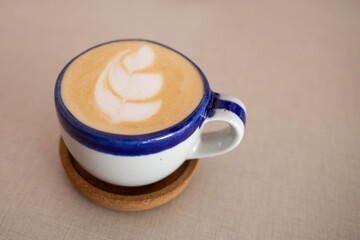 white and blue cup of cappuccino coffee on elegant vintage wooden table