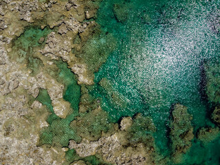 晴れた日の、沖縄県うるま市伊計島の透き通る海の干潮時の干潟の空からの写真
