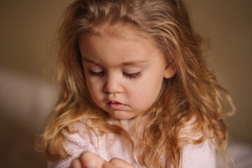 portrait of a beautiful little blonde girl in thought, long eyelashes