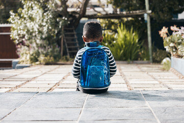 I hope Ill make some friends at school today. Shot of a little boy sitting outside with his backpack.