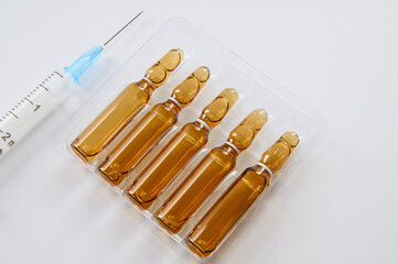 Dark glass ampoules in a package and a syringe on a white background