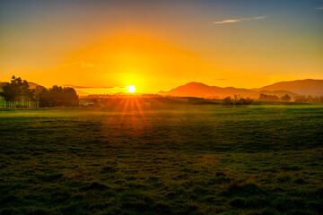 The sun going down over the hills and paddocks in the Catlins