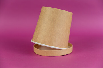 Empty cylindrical paper container with lid opposite-colored background. Brown food container for soup, ice cream, noodles, or other food.