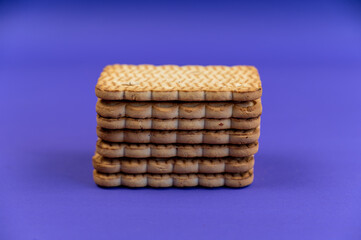 A stack of rectangular cookies against a blue background. Ready-to-eat treats with peanuts.
