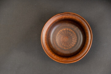An empty clay bowl against a black background. Brown new fired clay dishes. Selective focus.