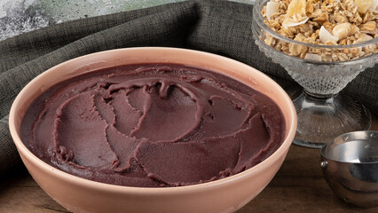 Portion of frozen açaí in a bowl and granola.