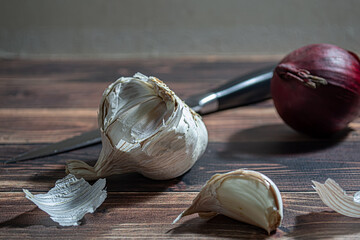 Fresh garlic bulbs and a garlic press on an old wooden board and a burlap backing.