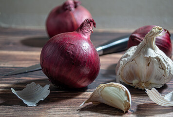 Fresh garlic bulbs and a garlic press on an old wooden board and a burlap backing.