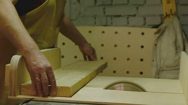 The master aligns 2 boards and saws them on a circular saw