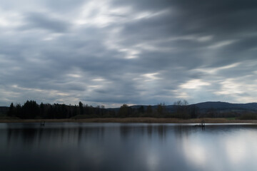 Small pond with tress under dramatic sky. Long exposure, Czech landscape