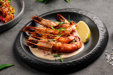 Portion of grilled tiger shrimp dish in a black plate
