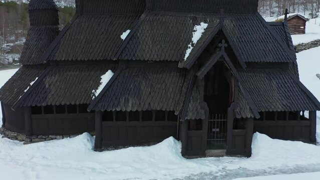 Borgund Stave church Norway - Winter low altitude aerial rotating slowly around entrance