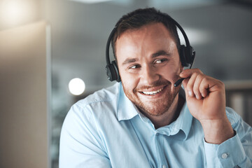 Youre speaking to one of our friendly agents. Shot of a young call centre agent sitting alone in his office and using his computer.