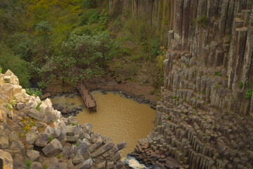 Columnas geom&eacute;tricas de roca bas&aacute;ltica rodean un peque&ntilde;o puente de madera