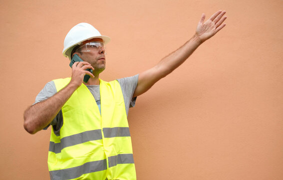 Surprised And Angry Foreman Talks On The Phone While Gesturing With His Hands.